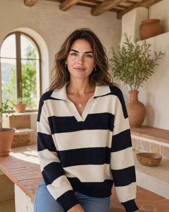 Mulher a usar camisola de malha Maria Pailona às riscas azul-marinho e creme com gola polo e decote em V.