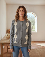 Mulher a usar cardigan Maria Pailona cinzento com padrão argyle, gola redonda e botões, em ambiente interior luminoso.