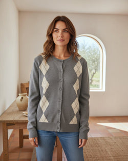 Mulher a usar cardigan Maria Pailona cinzento com padrão argyle, gola redonda e botões, em ambiente interior luminoso.